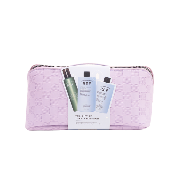 A lilac travel bag with silver zip on a transparent background. The bag has a cardboard band in the centre showcasing the three products inside. 