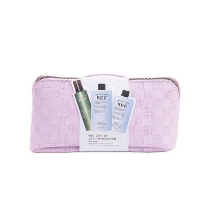 A lilac travel bag with silver zip on a transparent background. The bag has a cardboard band in the centre showcasing the three products inside. 