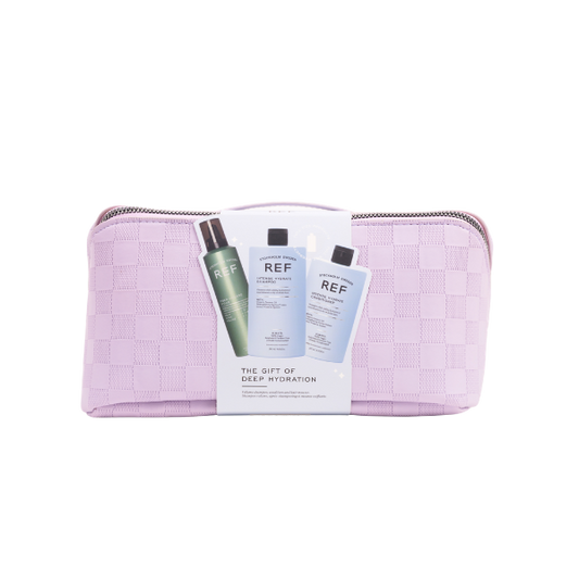 A lilac travel bag with silver zip on a transparent background. The bag has a cardboard band in the centre showcasing the three products inside. 